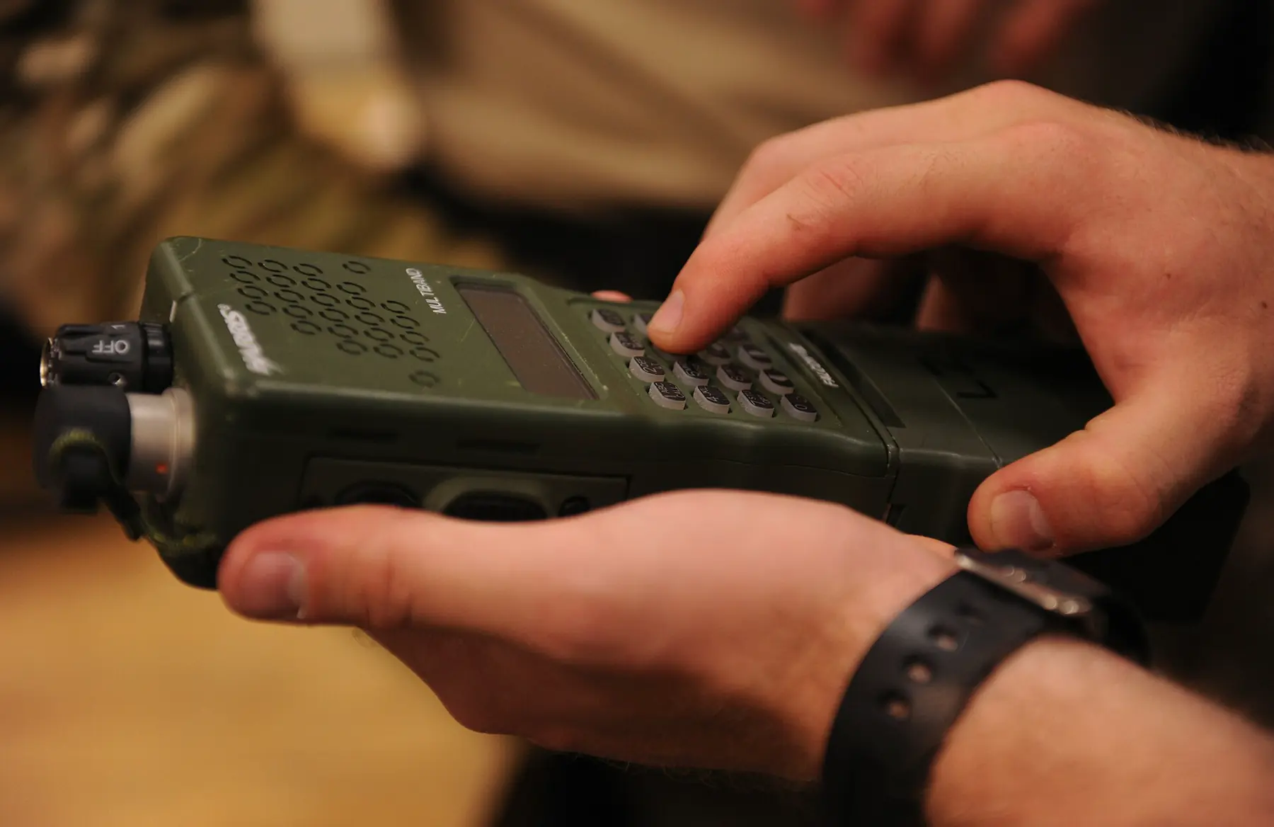 Close-up of hands configuring a handheld tactical radio