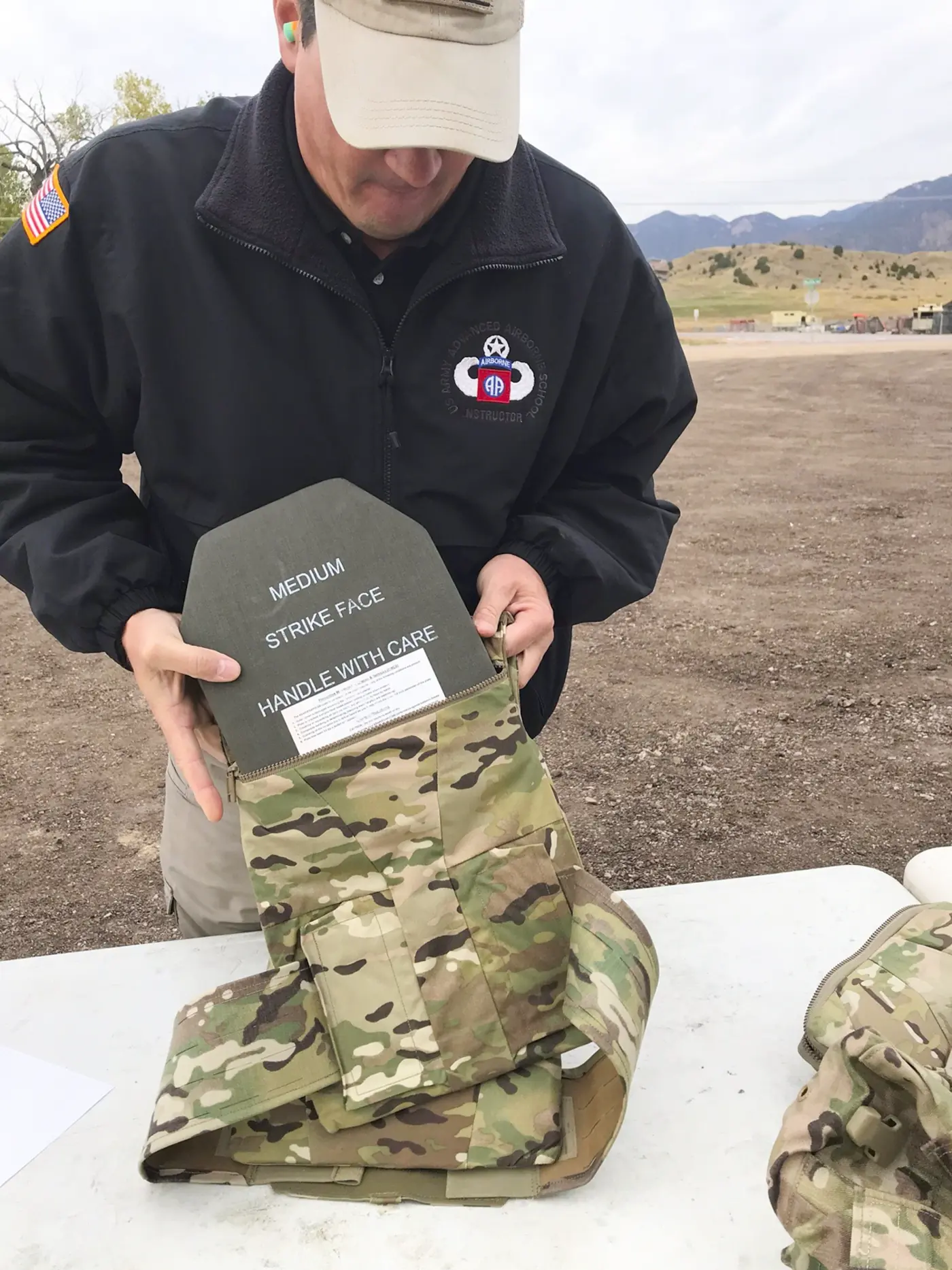 Instructor fitting a ballistic plate into a camouflage plate carrier
