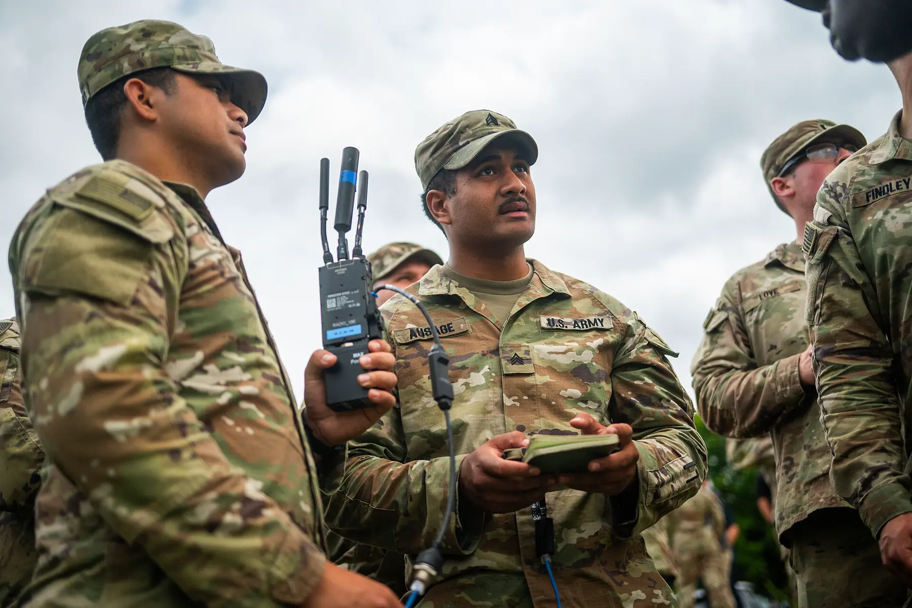 Personnel holding a handheld device and compact radio with antennas during an exercise